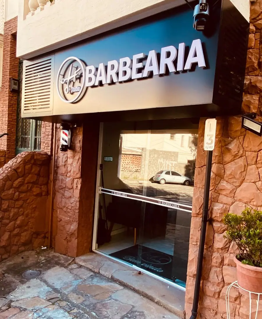 Entrada da barbearia com letreiro e poste de barbeiro
