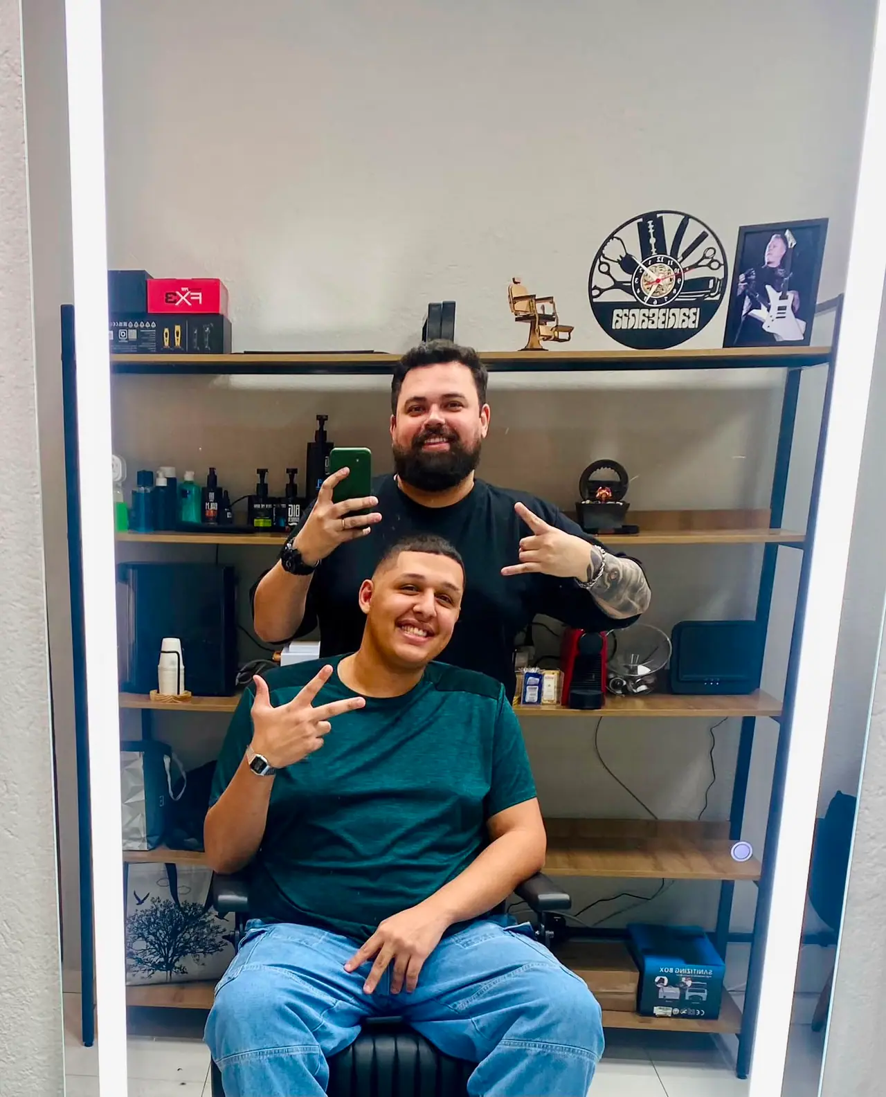Cliente de camiseta verde após o corte, com o barbeiro ao fundo