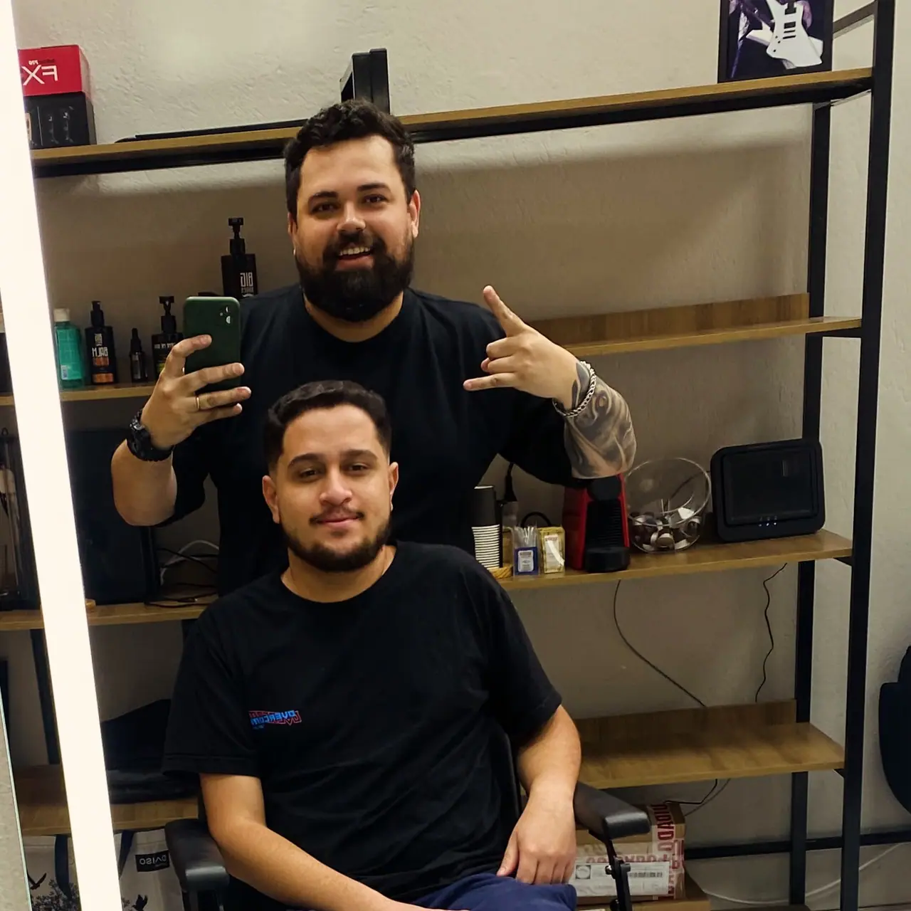 Cliente com corte e barba feitos, ao lado do barbeiro