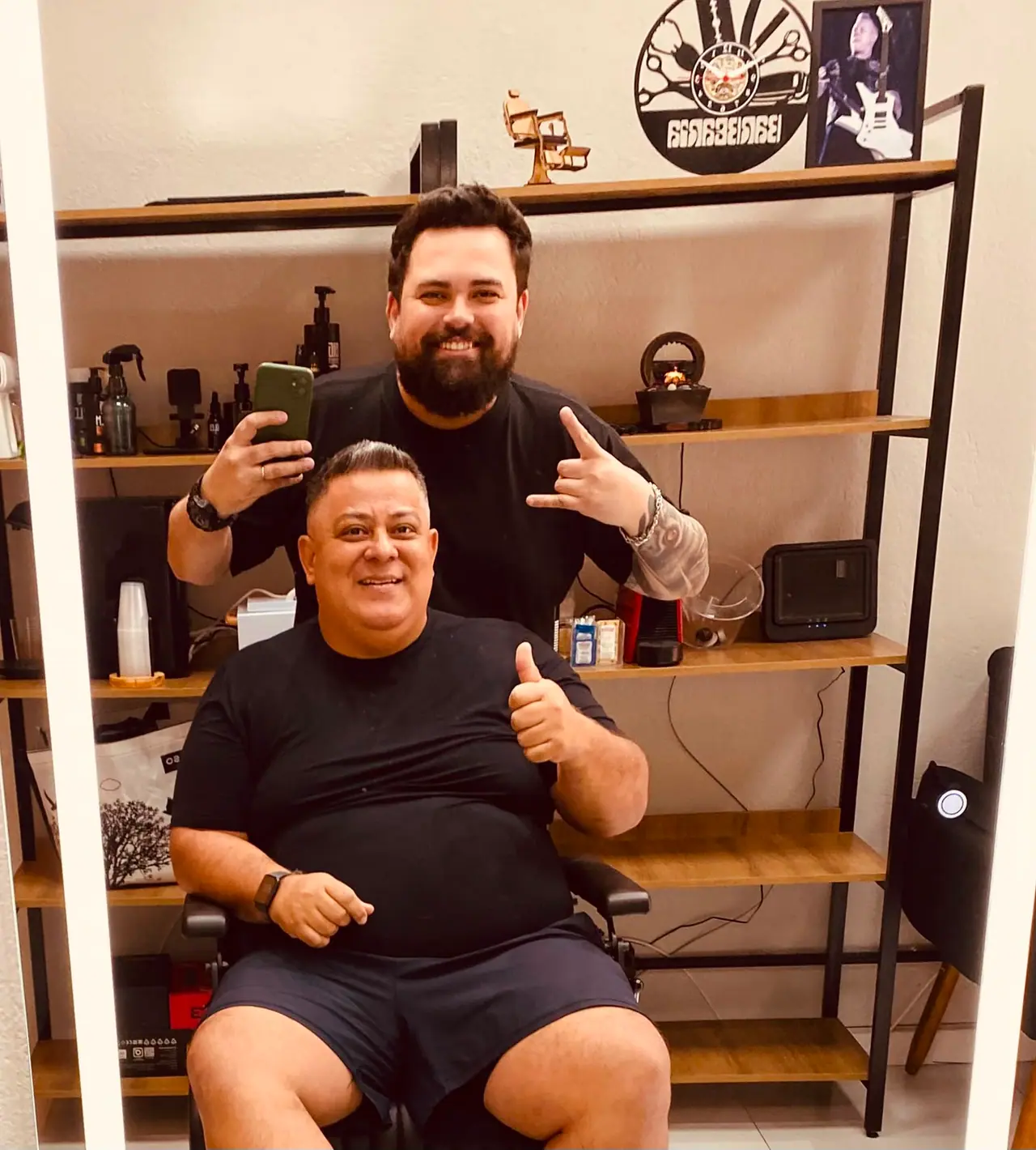 Cliente fazendo sinal de positivo após o atendimento, com o barbeiro ao fundo
