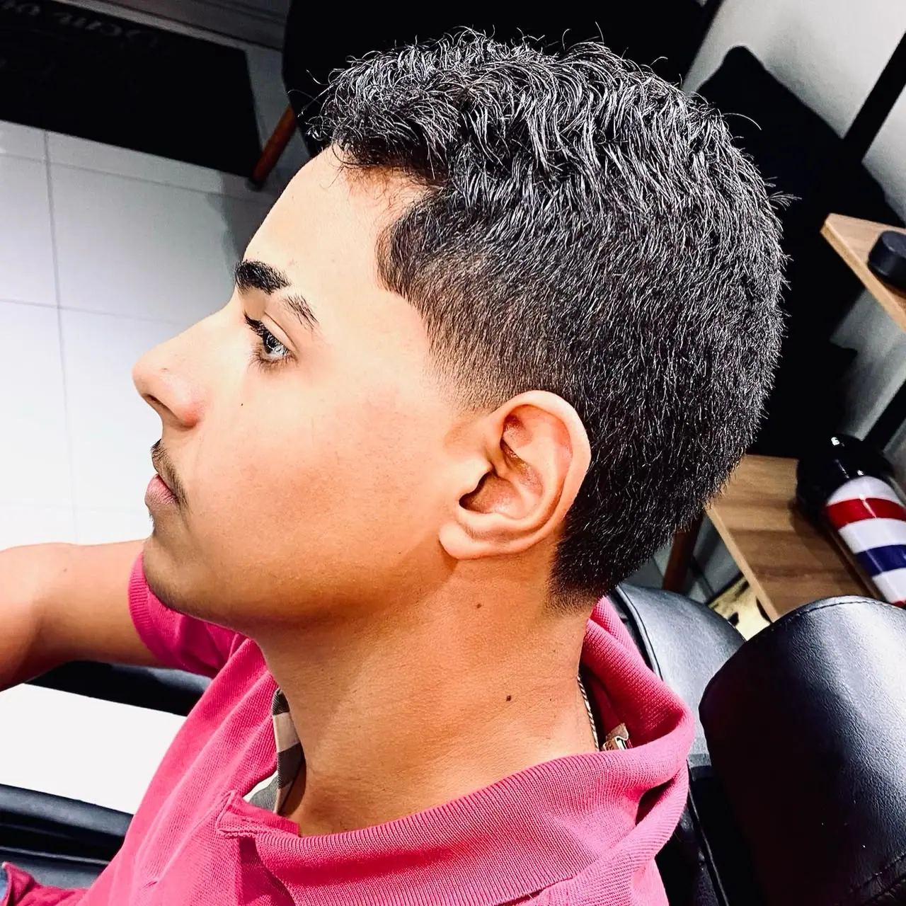 Cliente de perfil mostrando o corte com laterais baixas e topo cacheado